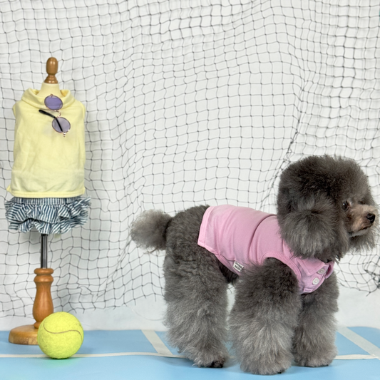 Luna (Silver Teacup Poodle) wearing the Pink Tennis Polo Tee (Available in 3 Colours) sold at Velymon SG standing in a blue Tennis Court.
