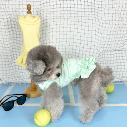 Nyxie (Silver Tiny Toy Poodle) wearing the MInt Tennis Polo Dress (Available in 3 Colours) sold at Velymon SG sitting in a Blue Tennis Court